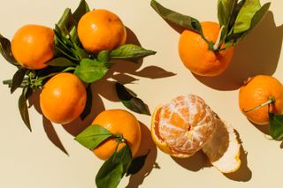 mandarin oranges, one of which is peeled