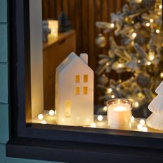 White Light Up House Decoration on a windowsill at Christmas