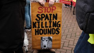 Protester holding placard saying 'stop Spain killing hounds'