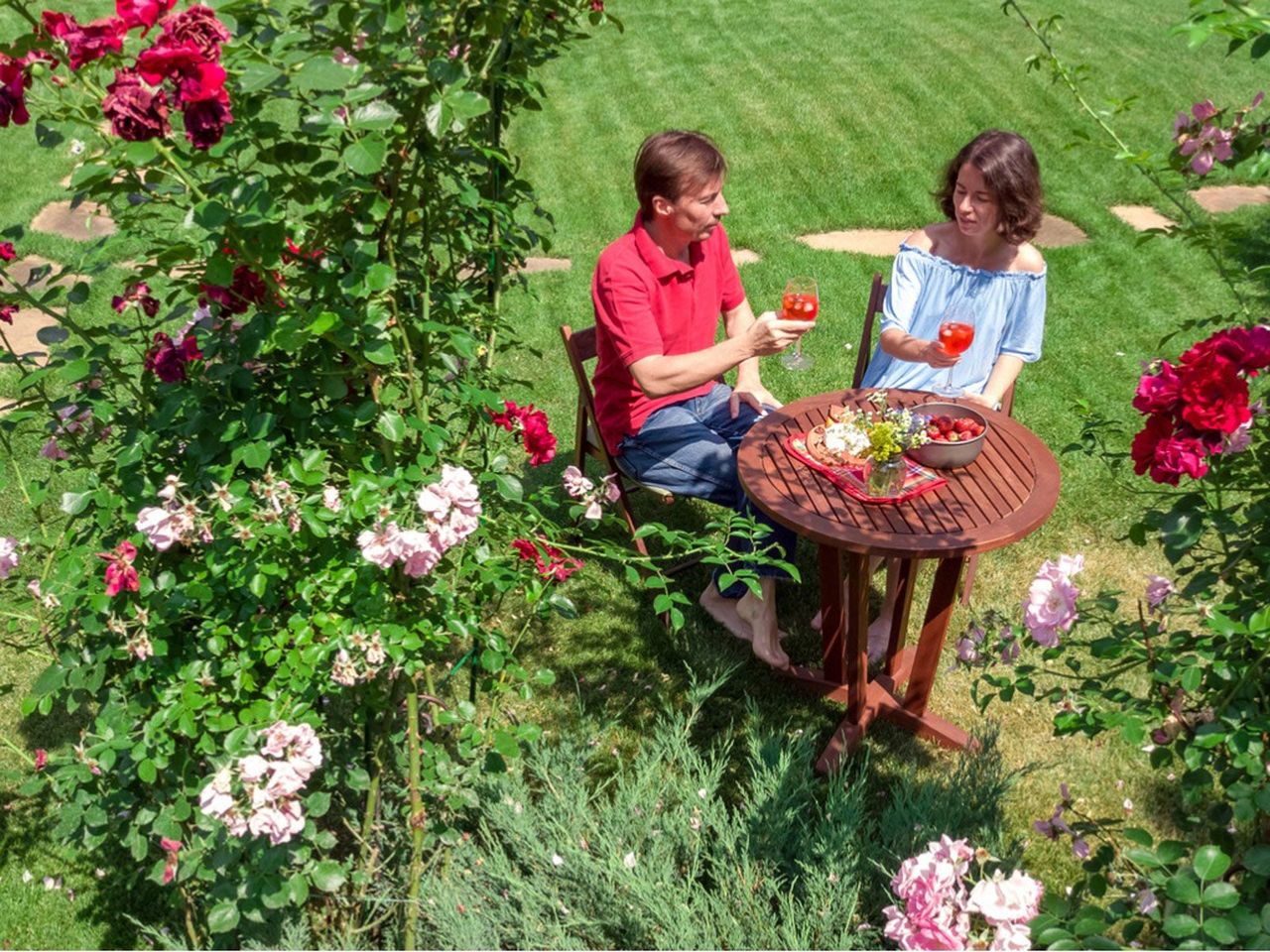 Couple Dining At An Outdoor Table Surrounded By Flowers