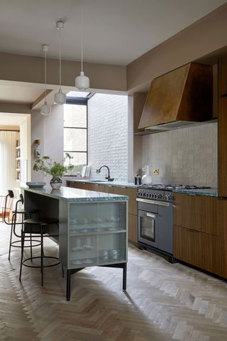 a kitchen with a small island, brass wood and wood cabinets, with a skylight at the back