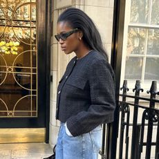 Woman wears black tweed jacket and blue jeans