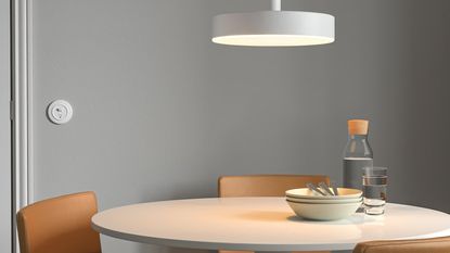 the IKEA smart pendant light in white sitting above a dining table