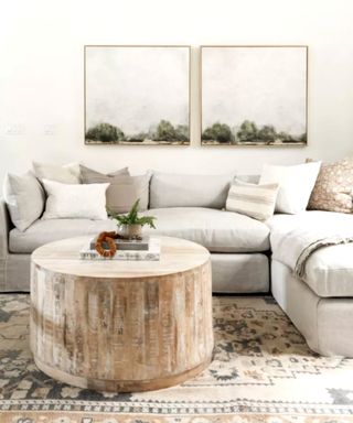 All white living room with wooden round table and sea canvases