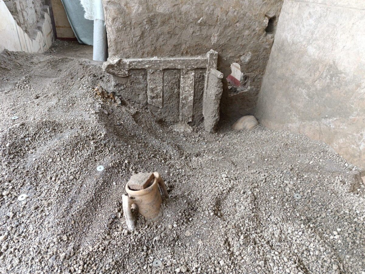 remains of a bed against a wal in a room filled with soot and dirt