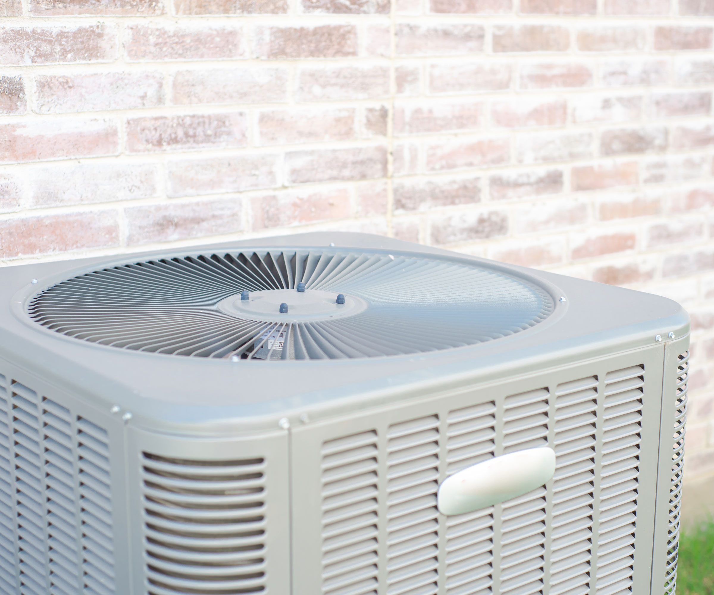 gray ac unit in backyard near walled side of house