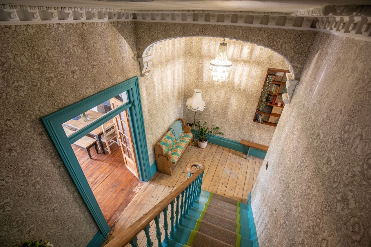 The staircase has wooden bannister and wooden flooring lines the bottom floor