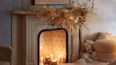 Cream stone fireplace with candles burning in the hearth and pampas grass decorations across the mantel