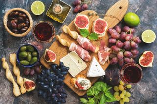 A variety of snacks, prosciutto,grapes, wine, cheese with mold, figs, olives on a rustic background. Top view,flat lay