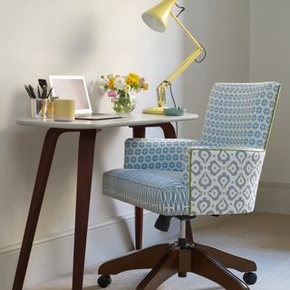 modern home office ideas, small mid century modern style desk space with yellow desk lamp, upholstered chair with blue and white pattern