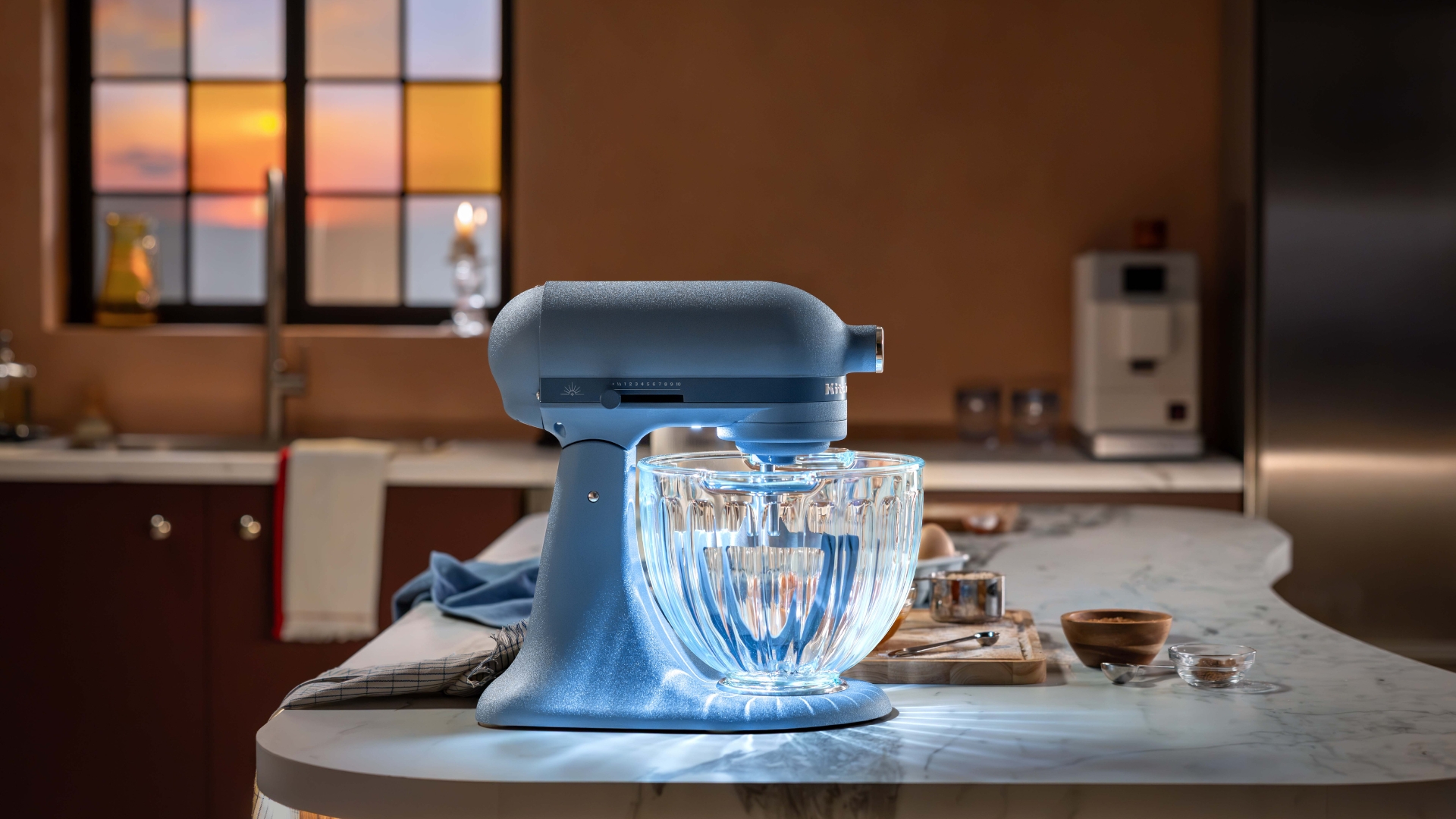 KitchenAid Luminaire Design Series Stand Mixer on a marble counter in a kitchen with the light on