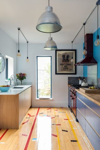 A small galley kitchen with wood flooring, dark blue cabinetry, wood countertops and lots of lightby Naked kitchens