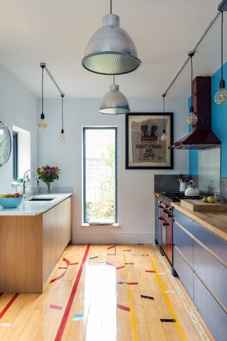 A small galley kitchen with wood flooring, dark cabinetry, wood countertops and lots of lightby Naked kitchens