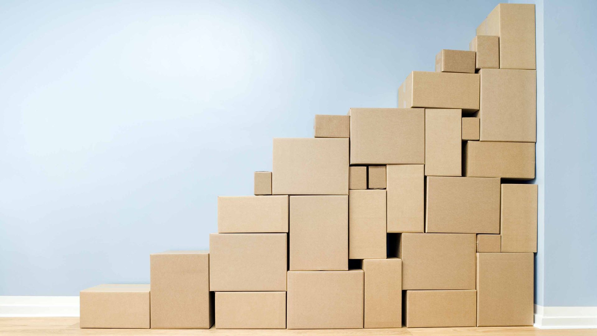 different sizes of cardboard boxes stacked against blue wall