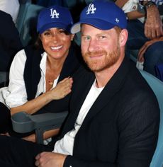 Meghan Markle and Prince Harry sitting in seats wearing Dodgers hats at the World series