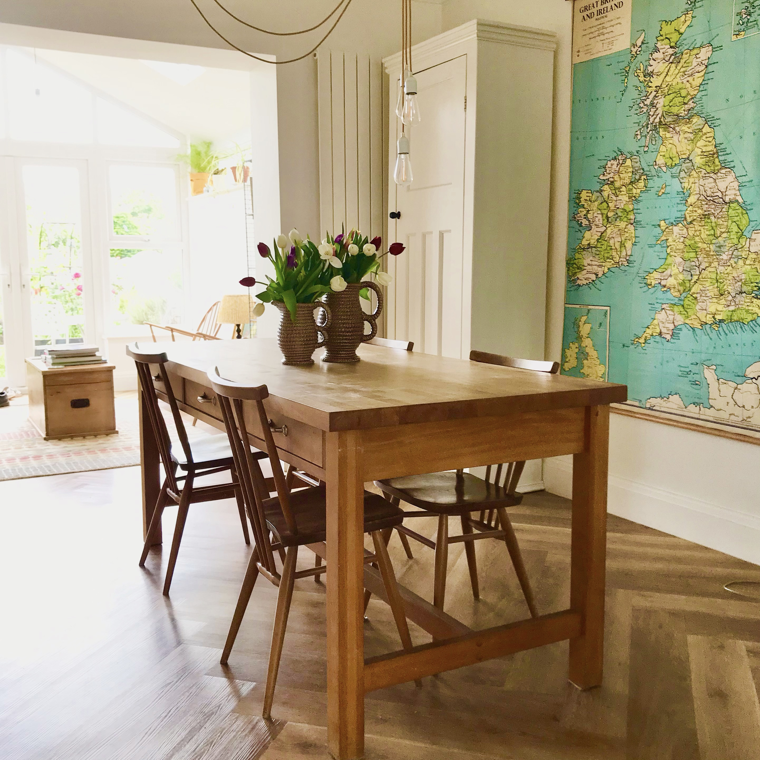 vintage wooden dining table and chairs in a cream dining room with a big map on the wall behind it