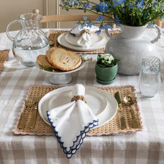 A table set with white and blue napkins and wicker napkin rings.
