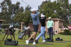 3 men, two swining golf clubs, one watching