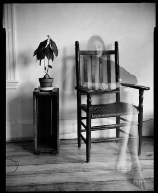 A transparent woman sitting on a chair