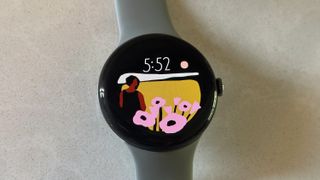 The Google Pixel Watch 3 on a white counter, showing the Vista watch face.