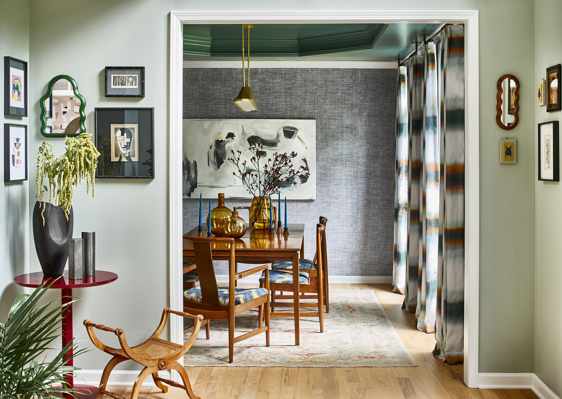 Different shades of green work harmoniously with orange and brown-tinged wood and blue accents in this hallway and dining room.