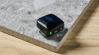 The DJI Mic Mini in black on a stone surface.