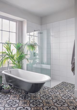 Black and white bathroom with Moorish patterned floor tiles and bateau bath and shower cubicle
