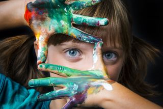 A young girl with watercolor on her hands.