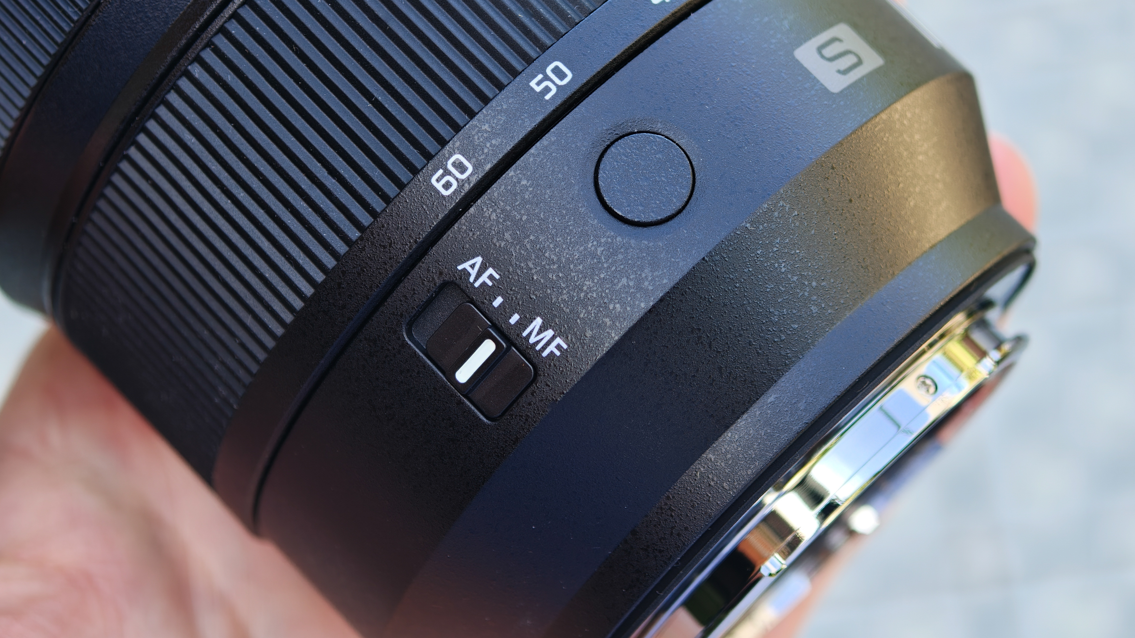 Panasonic Lumix S 24-60mm f/2.8 lens held in a hand