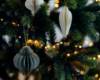Scandinavian christmas paper honeycomb ornament on Christmas tree with lights