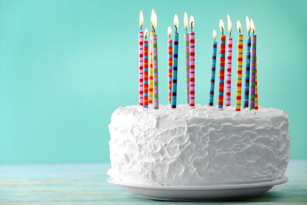 A blue happy birthday cake with candles on it