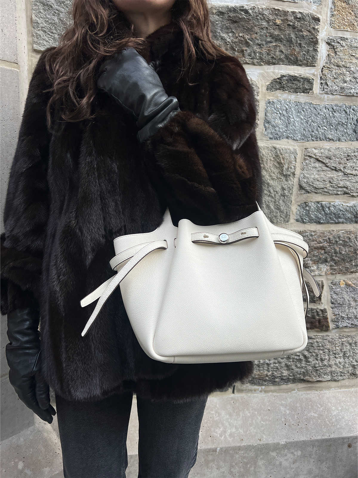 Eliza Huber testing out the Tory Burch Romy Small Tote Bag in cream with a brown fur coat, black jeans, and black heels.