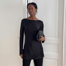 Influencer @sylviemus_ wears a black satin blouse with black capri pants and heeled mules.