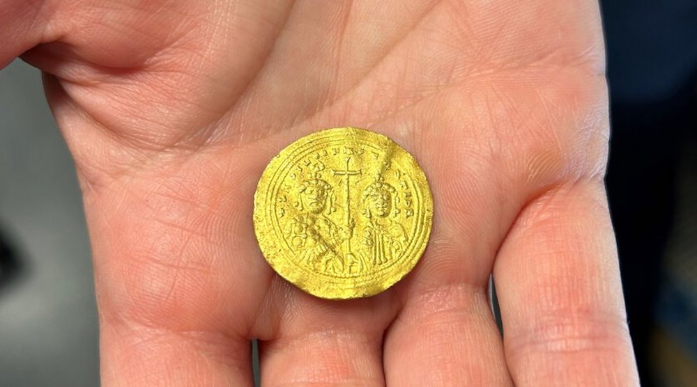 A person holds a gold coin.