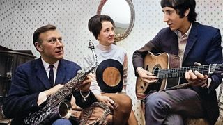 Pete Townshend of The Who pictured playing an acoustic guitar with his father Cliff Townshend (1916-1986), saxophone player with the Squadronaires, and mother Betty at home in London on 30th March 1966.