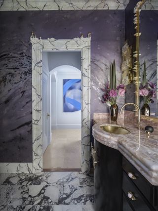 A grand purple bathroom featuring marble and gold