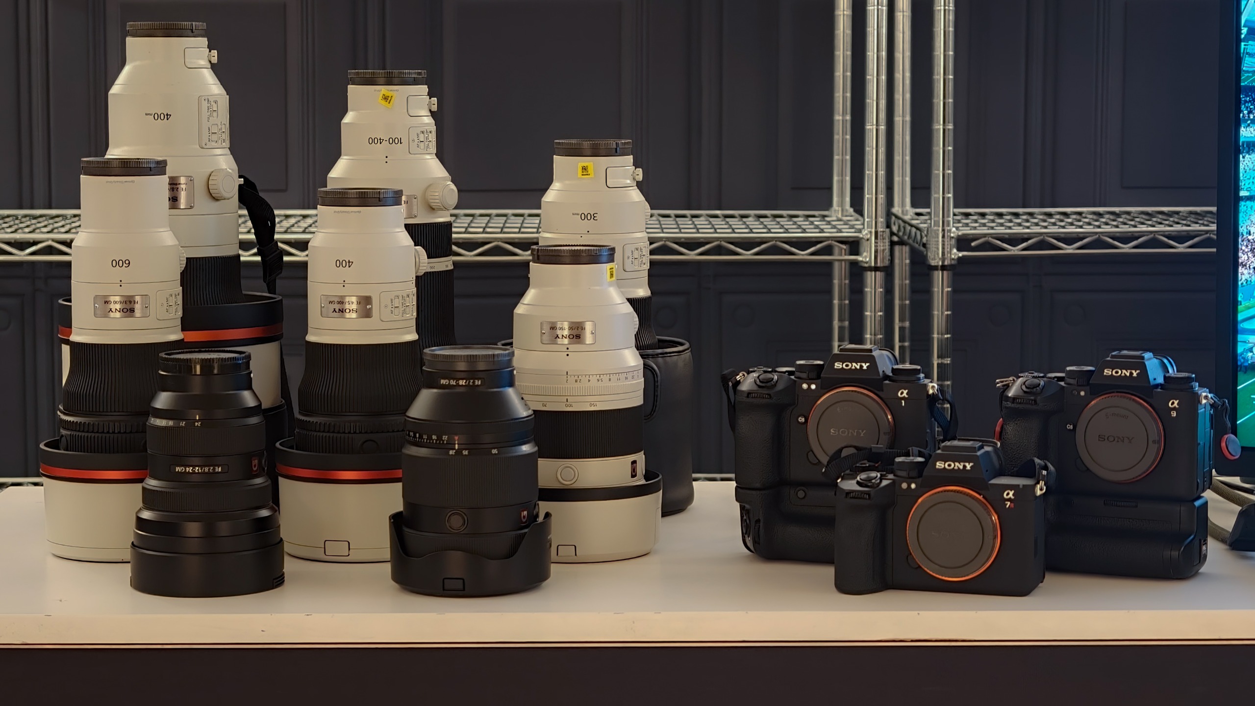 Collection of Sony Alpha camera bodies and large Sony telephoto lenses arranged on a table.