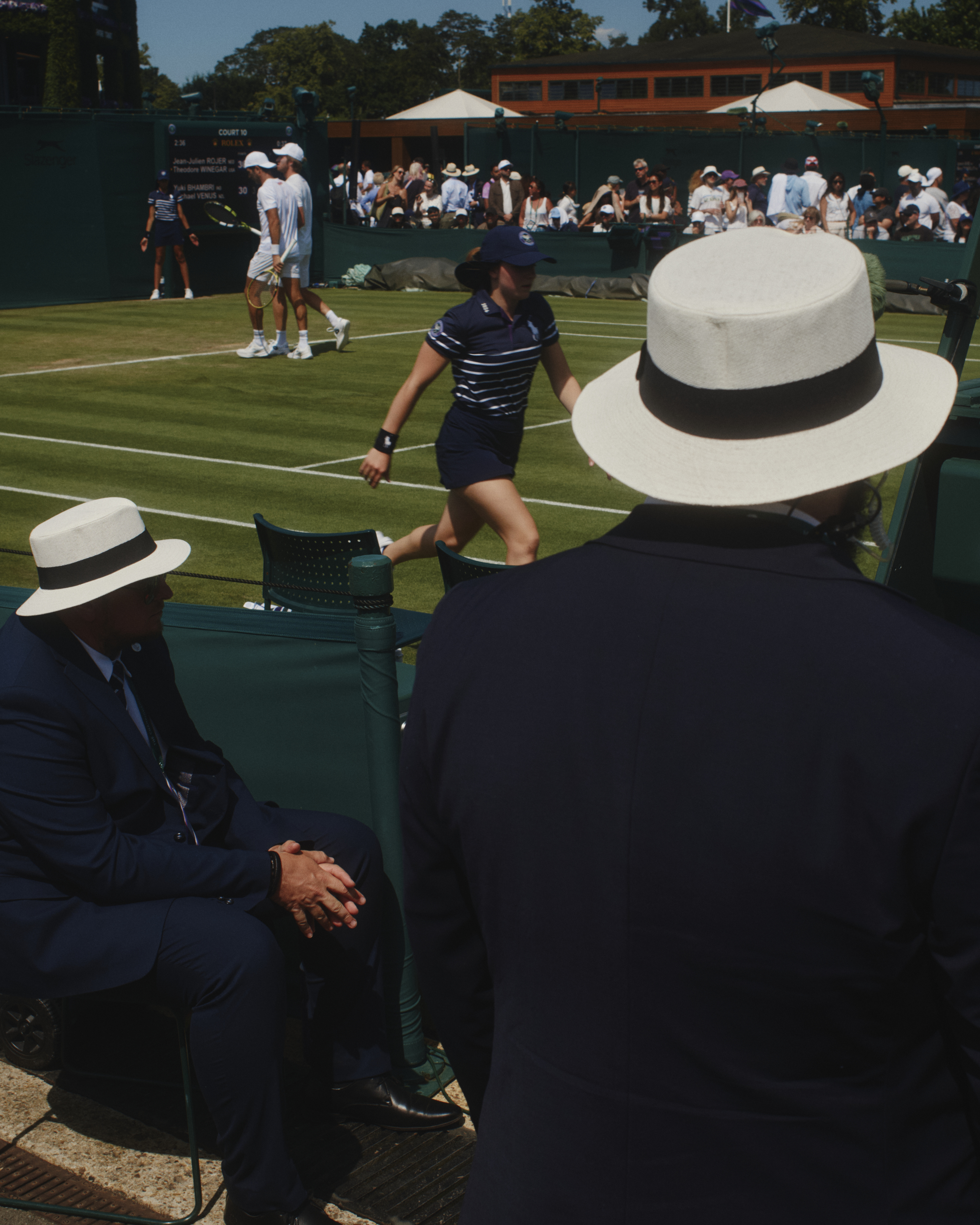 Gentlemen in hats, from behind, watching tennis at Wimbledon
