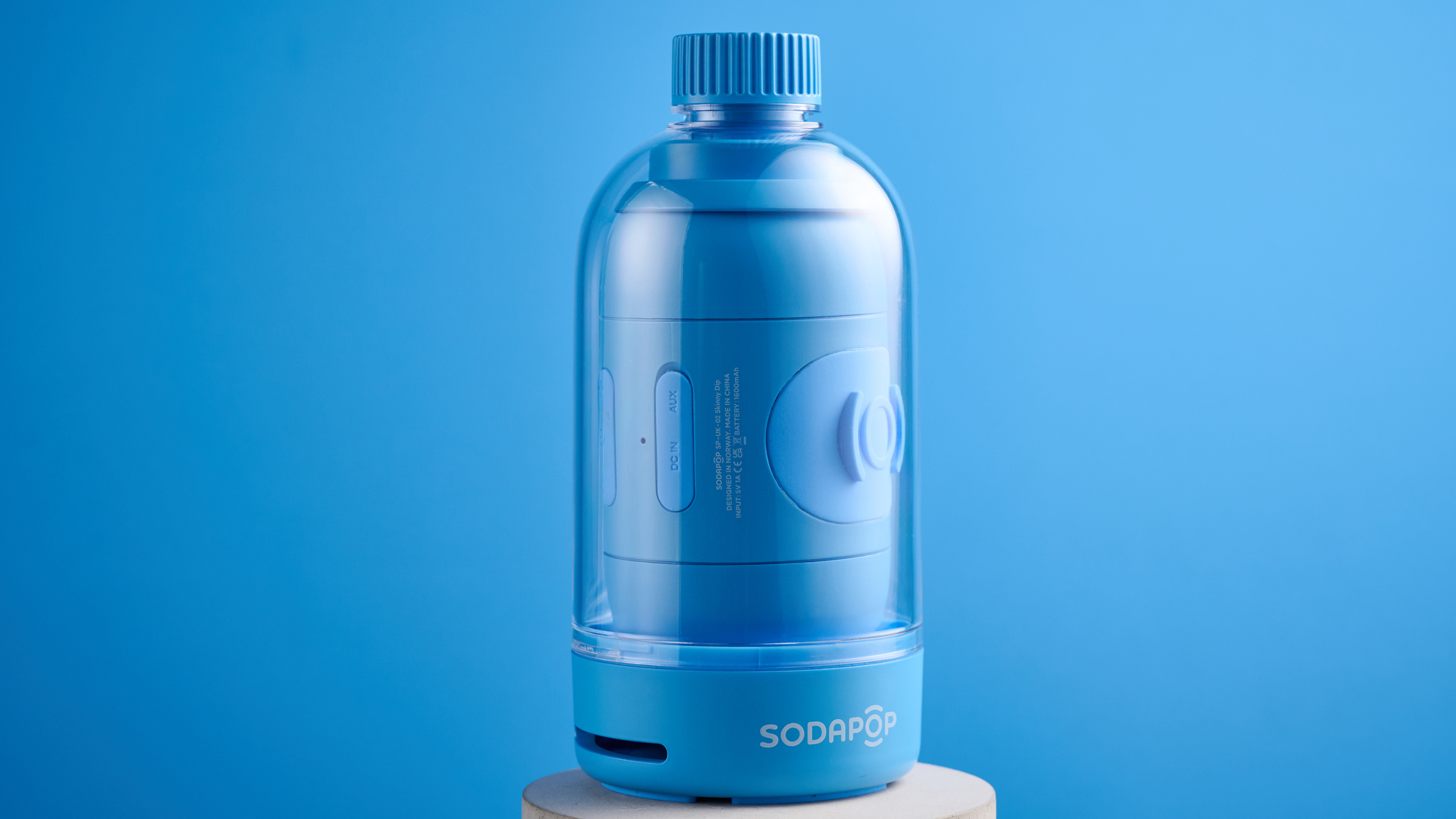 A blue Sodapop Bluetooth speaker that screws onto any regular-sized bottle