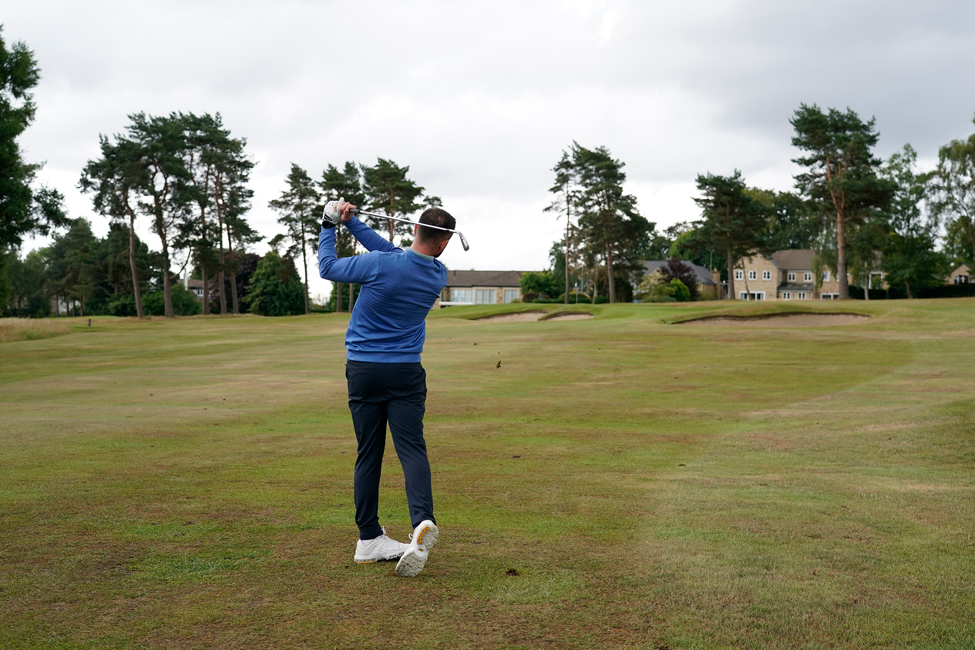 Baz Plummer in the finish position of his golf swing after hitting an approach shot with an iron towards the green at Sand Moor Golf Club