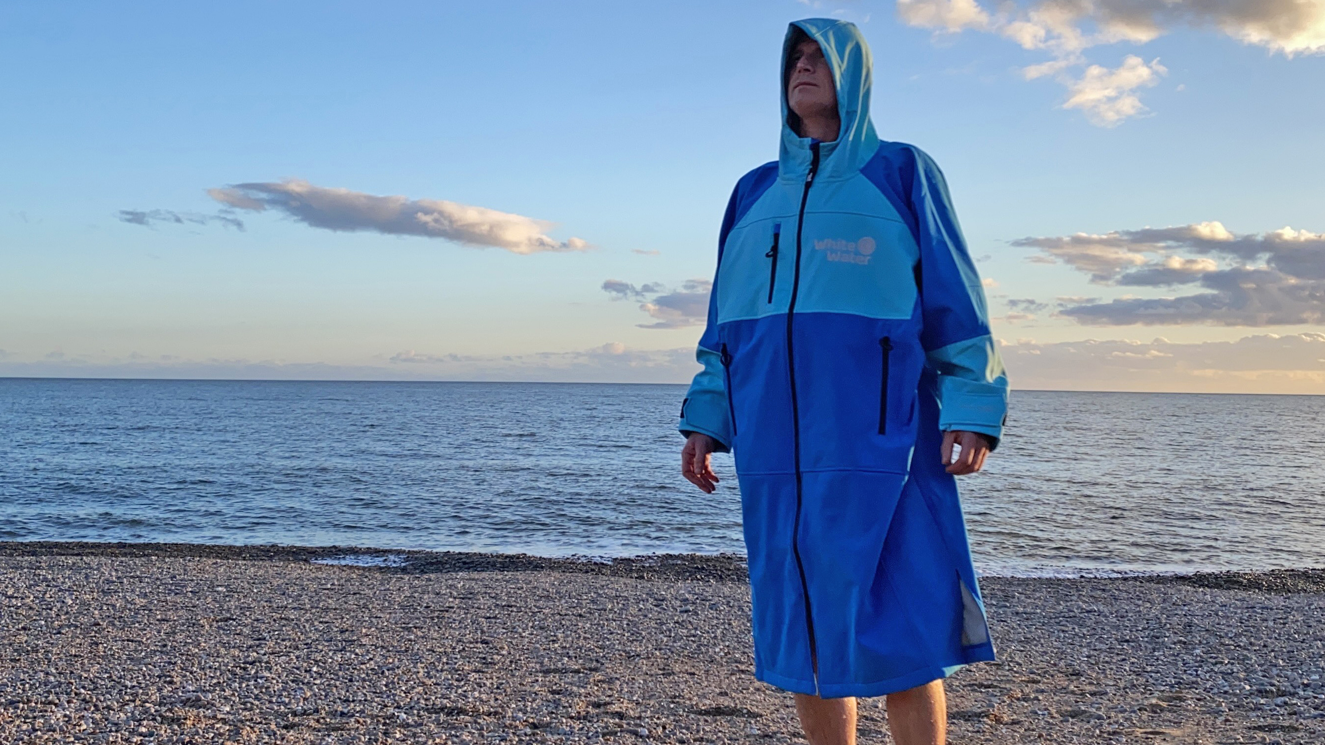 Pat Kinsella wearing the Whitewater Softshell Robe on a pebble beach