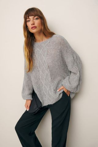 reformation winter sale woman wearing light grey oversized cable jumper
