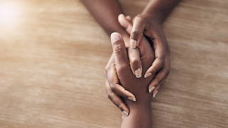 Women holding hands supportively