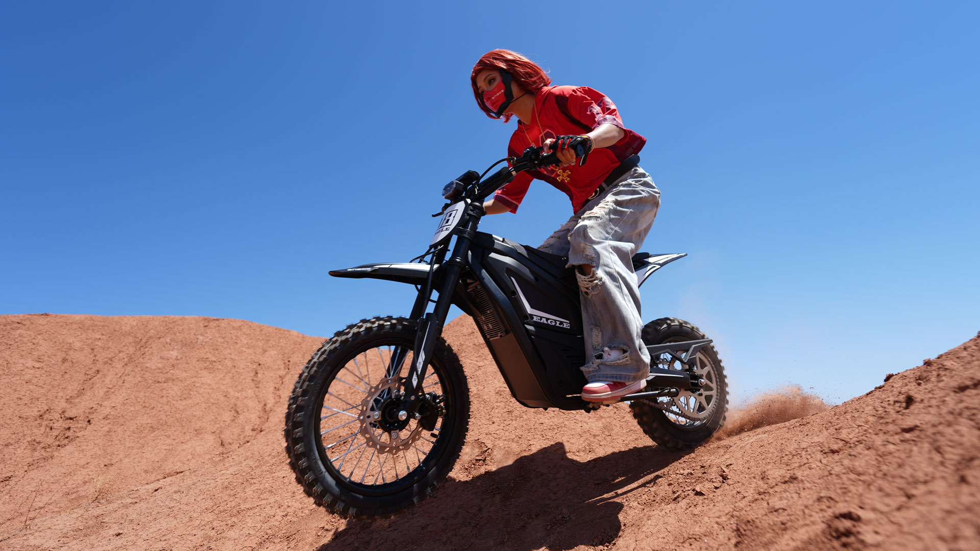 A young person riding the ENGWE Eagle across sand dunes