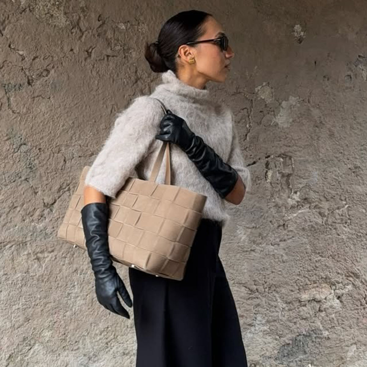 Woman wearing a gray short sleeve sweater and long sleeve black leather gloves