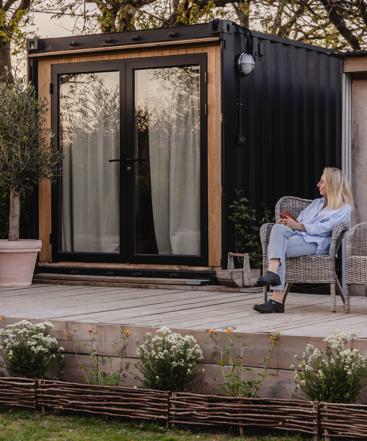 Abbie sitting outside the renovated shipping container on the decking outside it
