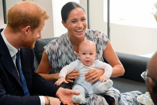 Meghan holding her son Archie as Prince Harry looks on