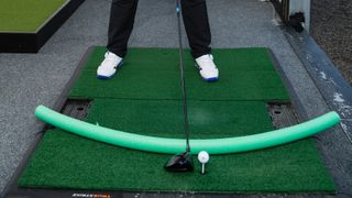 PGA pro Ged Walters setting up to the ball with a swimming noodle demonstrating the ideal swing plane
