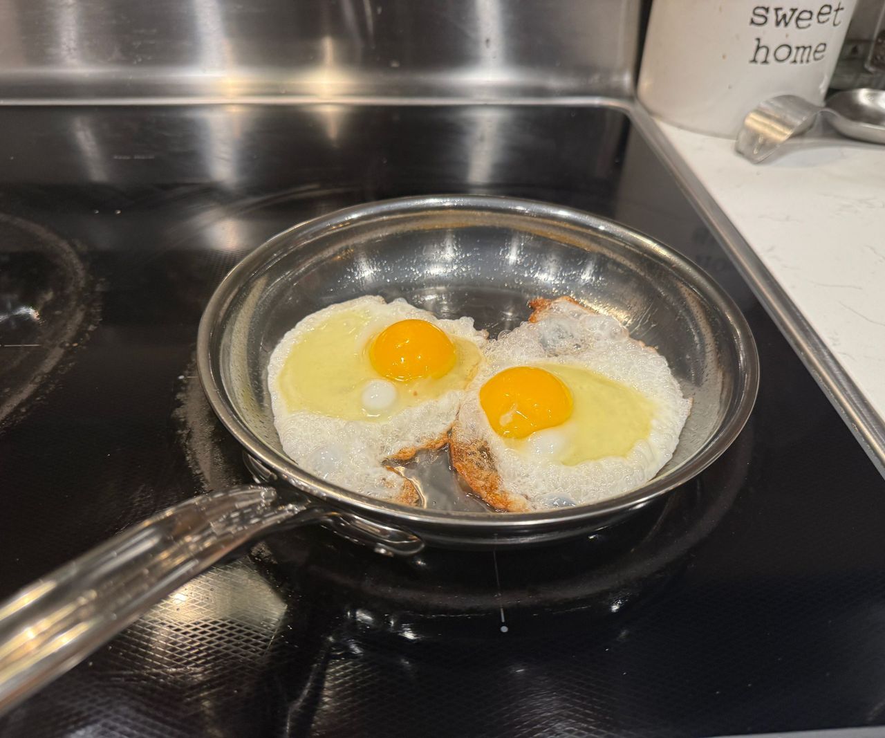 The Hestan NanoBond Skillet frying two eggs on a black stovetop