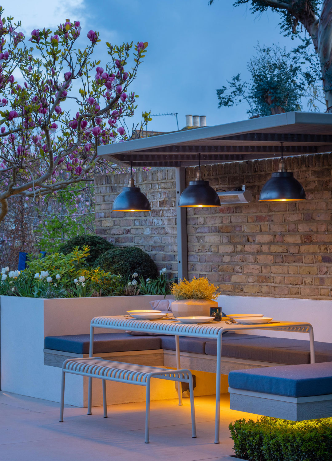 outdoor dining area with pendant lighting and metal table and chairs